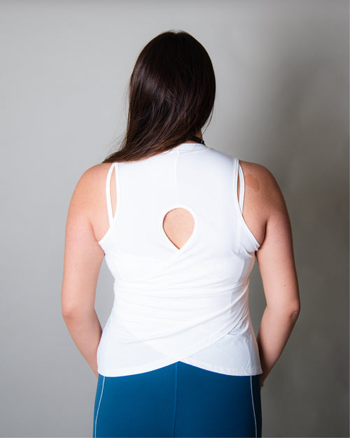 Blusa deportiva blanca sin mangas tipo tank top para mujer, de diseño ligero y versátil que permite libertad total de movimiento y mayor ventilación en la espalda, ideal para entrenamiento y uso activo diario.