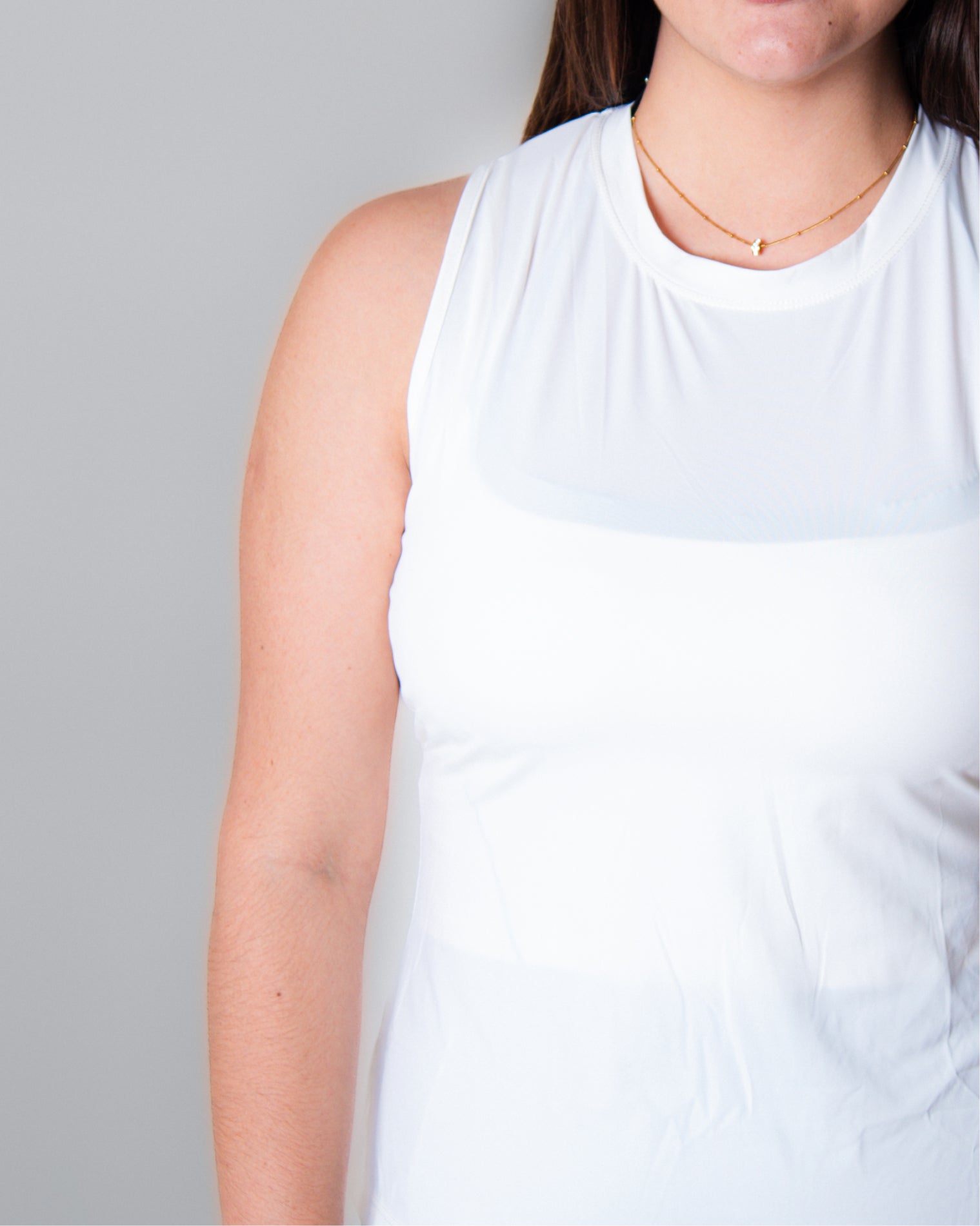 Blusa deportiva blanca sin mangas tipo tank top para mujer, de diseño ligero y versátil que permite libertad total de movimiento y mayor ventilación en la espalda, ideal para entrenamiento y uso activo diario.