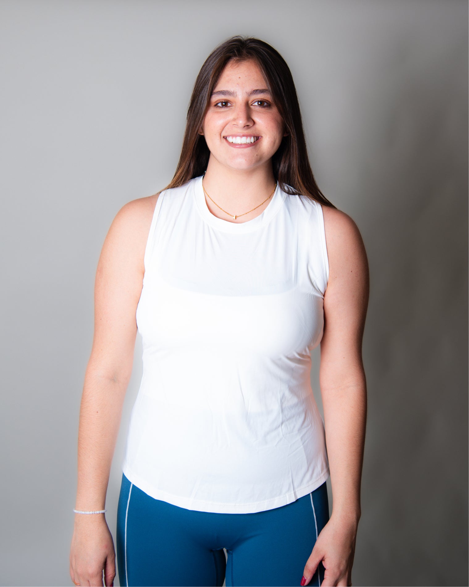 Blusa deportiva blanca sin mangas tipo tank top para mujer, de diseño ligero y versátil que permite libertad total de movimiento y mayor ventilación en la espalda, ideal para entrenamiento y uso activo diario.