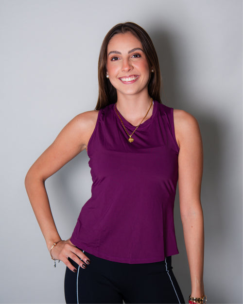 Blusa deportiva morada sin mangas tipo tank top para mujer, de diseño ligero y versátil que permite libertad total de movimiento y mayor ventilación en la espalda, ideal para entrenamiento y uso activo diario.
