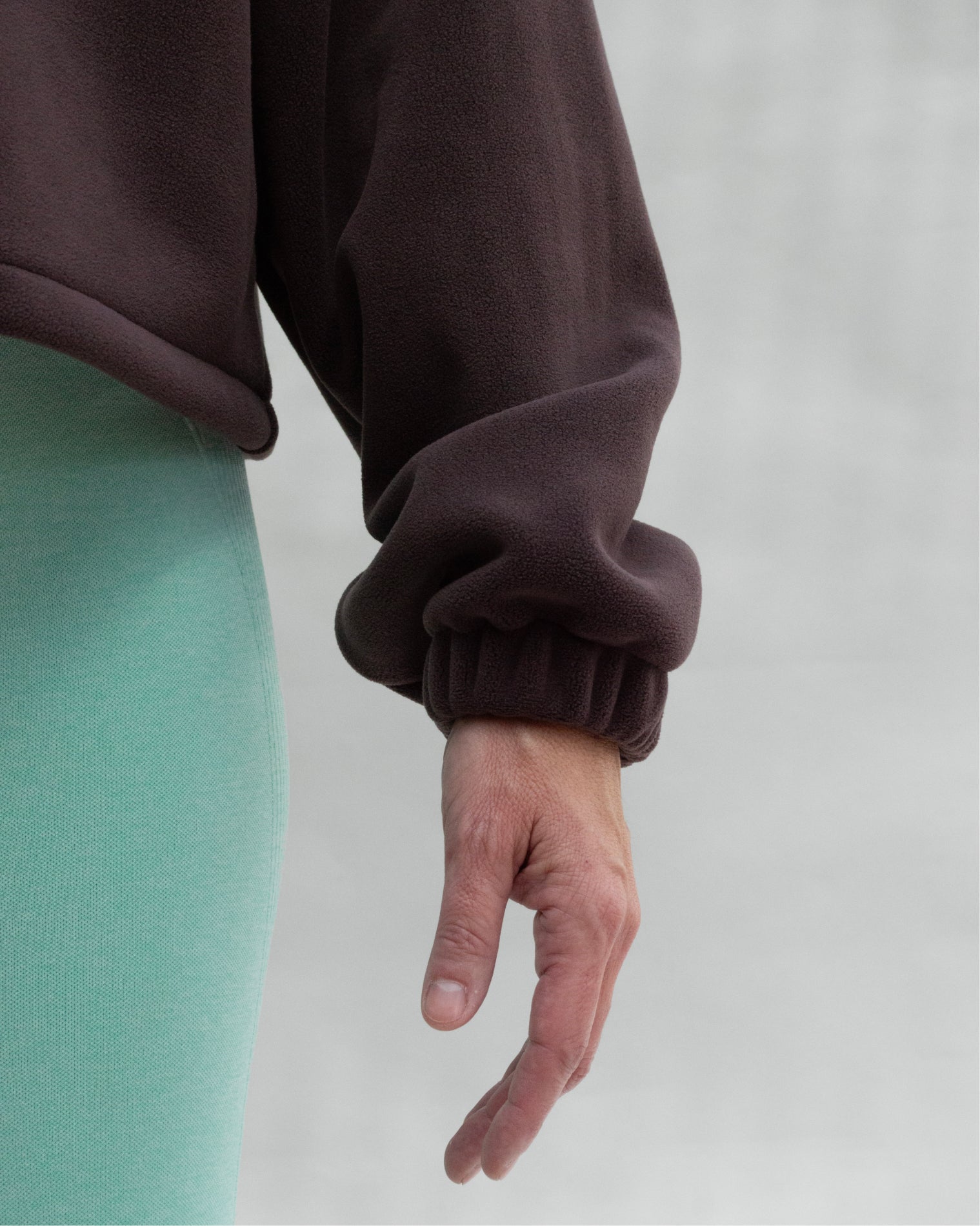 Chamarra deportiva oversize para mujer en tono café con cierre frontal y ajuste inferior regulable, confeccionada en tela afelpada de tacto suave, ideal para brindar abrigo ligero y comodidad antes o después del entrenamiento.