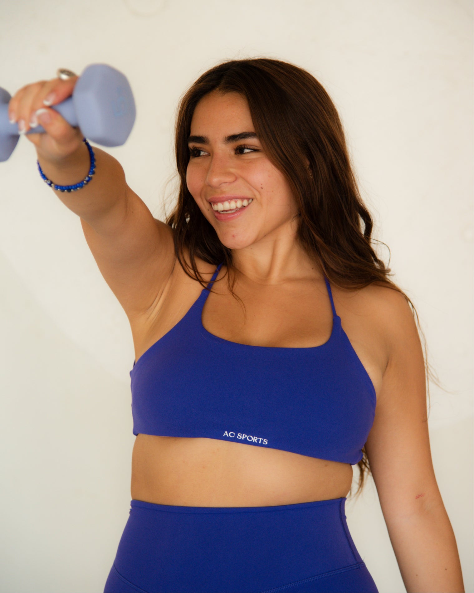 Top deportivo Azul para mujer con tirantes finos y escote recto, ajuste ceñido al cuerpo y acabado liso, con logo AC Sports al frente. Combinado con leggings de tiro alto, ideal para entrenamientos de bajo impacto y uso diario.