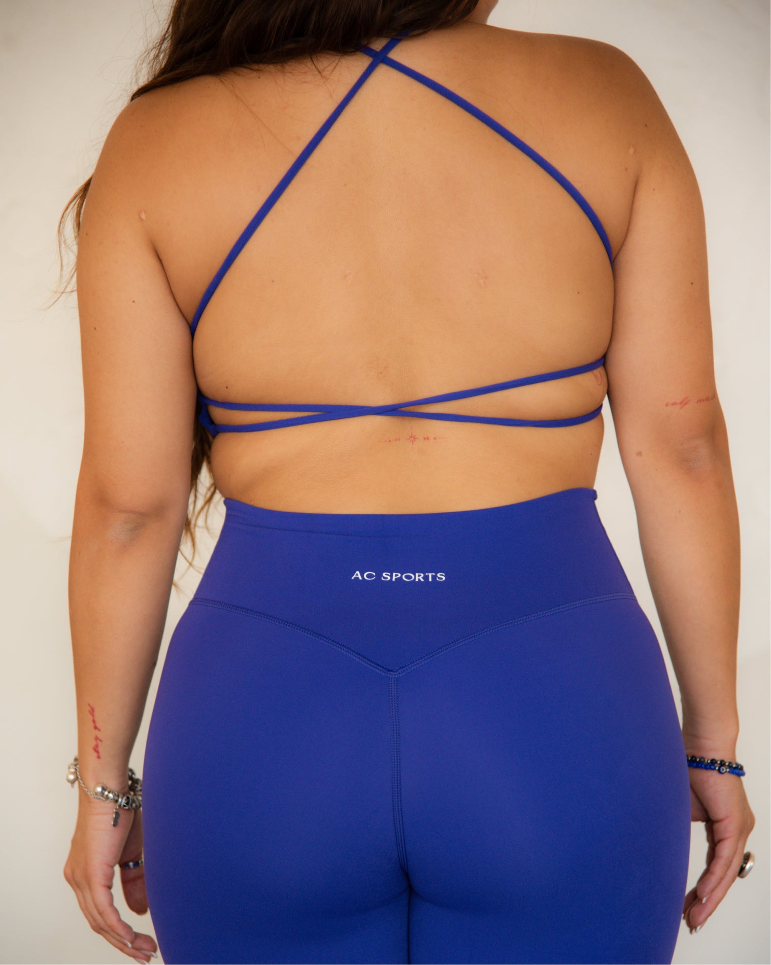 Top deportivo Azul para mujer con tirantes finos y escote recto, ajuste ceñido al cuerpo y acabado liso, con logo AC Sports al frente. Combinado con leggings de tiro alto, ideal para entrenamientos de bajo impacto y uso diario.