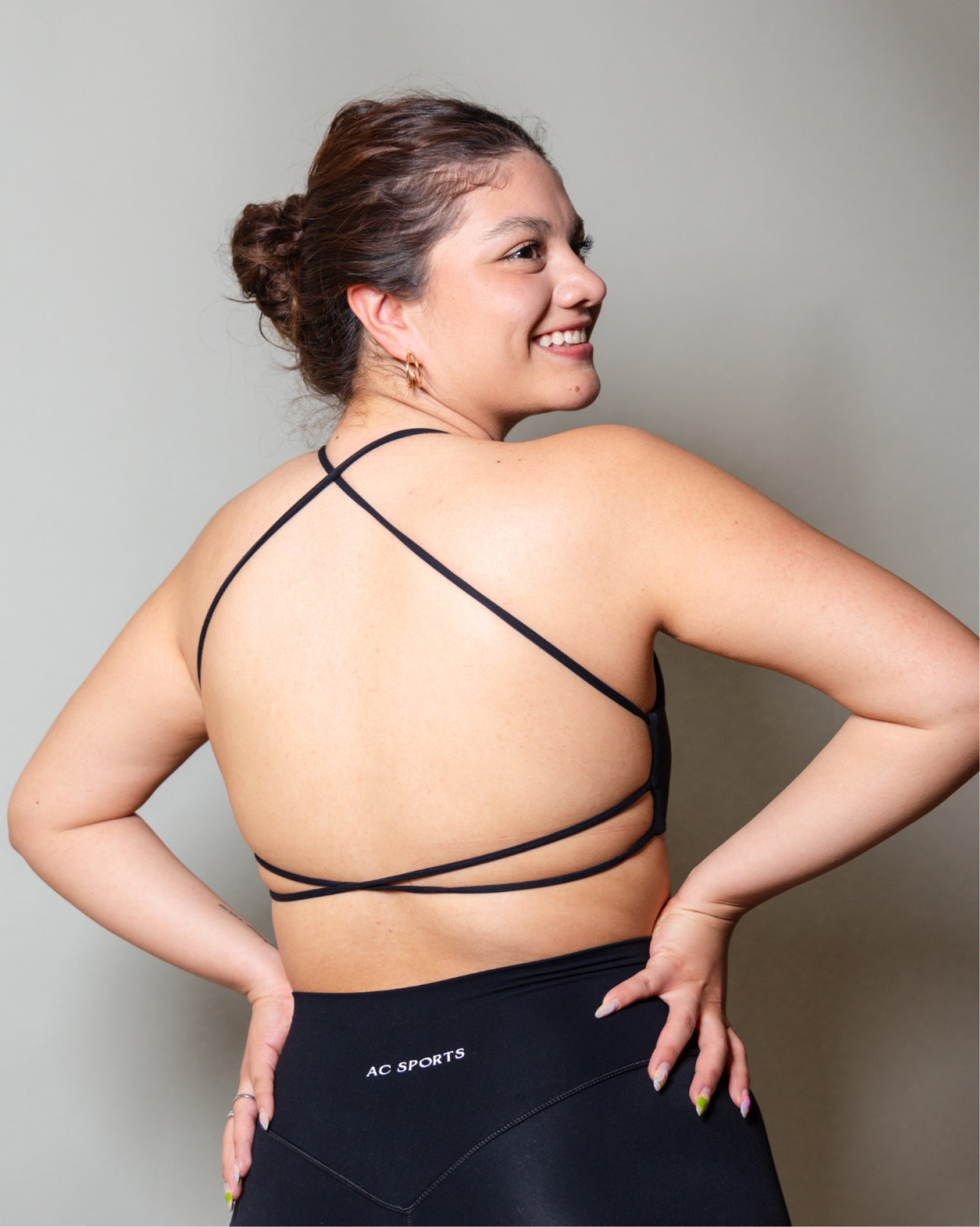 Top deportivo Negro para mujer con tirantes finos y escote recto, ajuste ceñido al cuerpo y acabado liso, con logo AC Sports al frente. Combinado con leggings de tiro alto, ideal para entrenamientos de bajo impacto y uso diario.