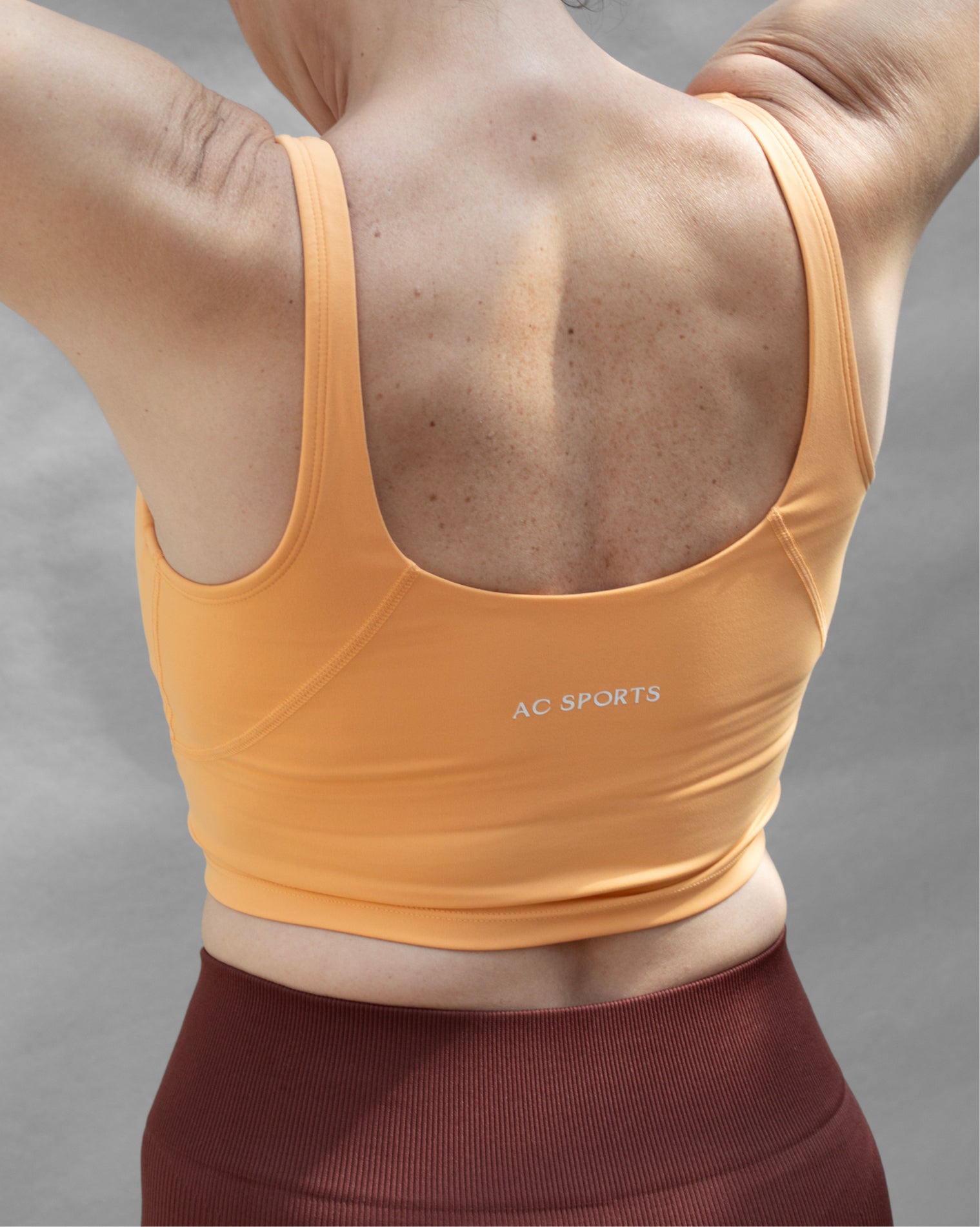 Top deportivo naranja tipo tank para mujer, con tirantes anchos y escote redondeado, mayor cobertura en el pecho y ajuste ceñido al cuerpo. Diseño liso de estilo deportivo, ideal para entrenar o usar en actividades diarias.