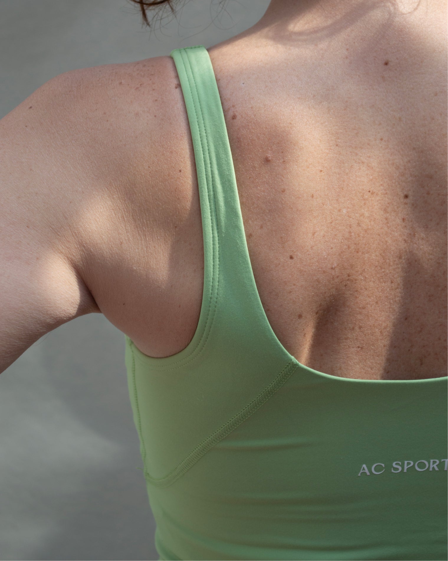 Top deportivo verde tipo tank para mujer, con tirantes anchos y escote redondeado, mayor cobertura en el pecho y ajuste ceñido al cuerpo. Diseño liso de estilo deportivo, ideal para entrenar o usar en actividades diarias.