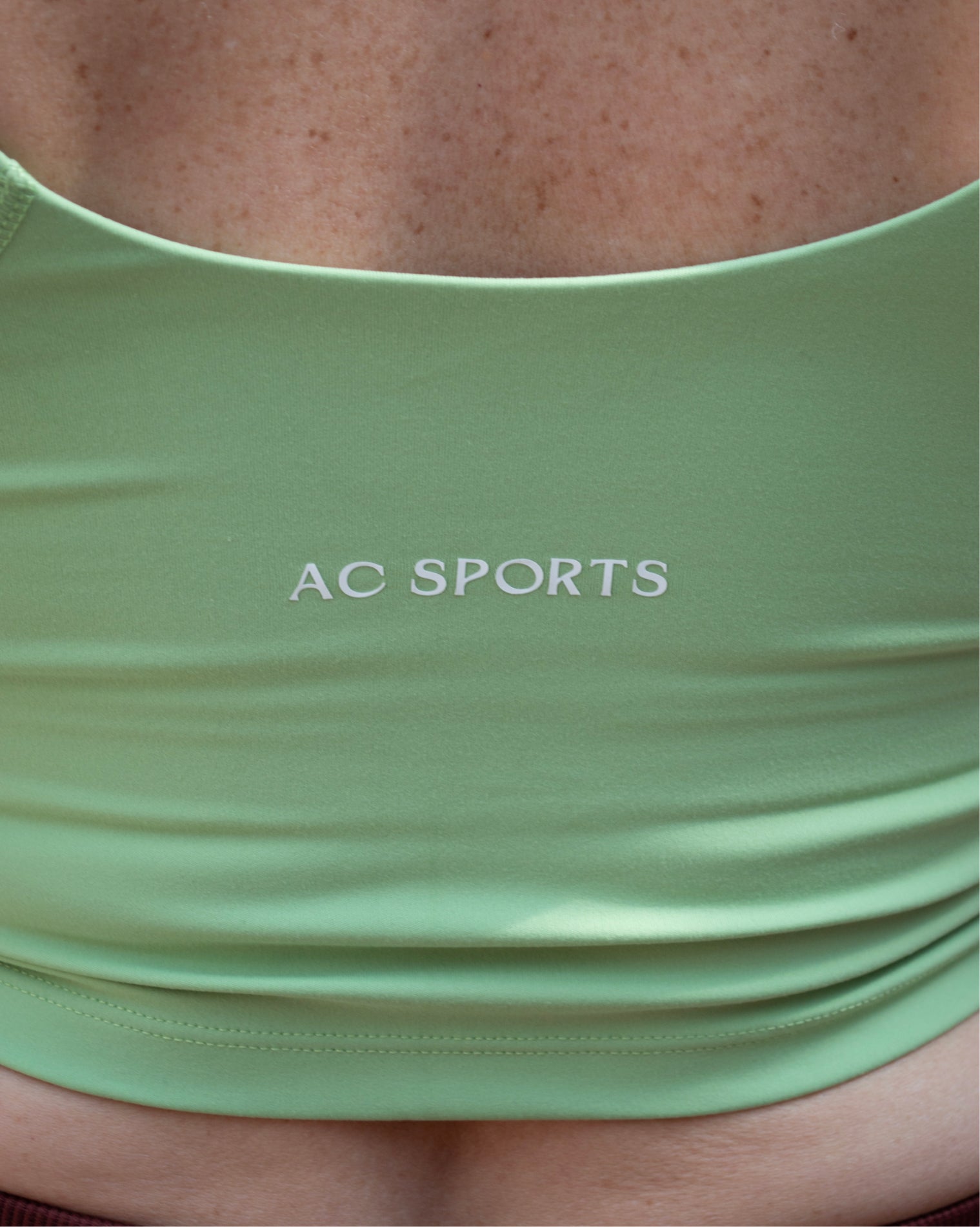 Top deportivo verde tipo tank para mujer, con tirantes anchos y escote redondeado, mayor cobertura en el pecho y ajuste ceñido al cuerpo. Diseño liso de estilo deportivo, ideal para entrenar o usar en actividades diarias.