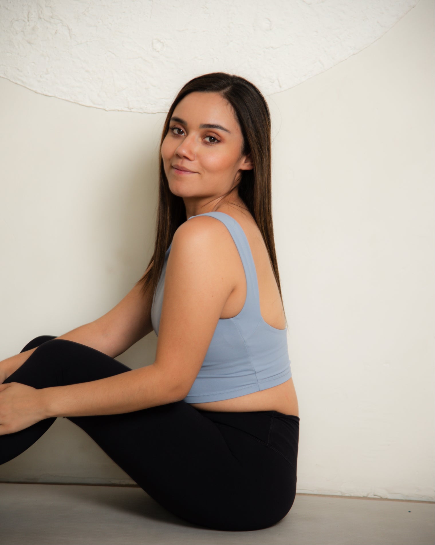 Top deportivo largo azul claro para mujer, diseño sin mangas tipo tank con escote alto y mayor cobertura, ajuste ceñido al cuerpo y acabado liso, ideal para entrenamiento y uso diario.