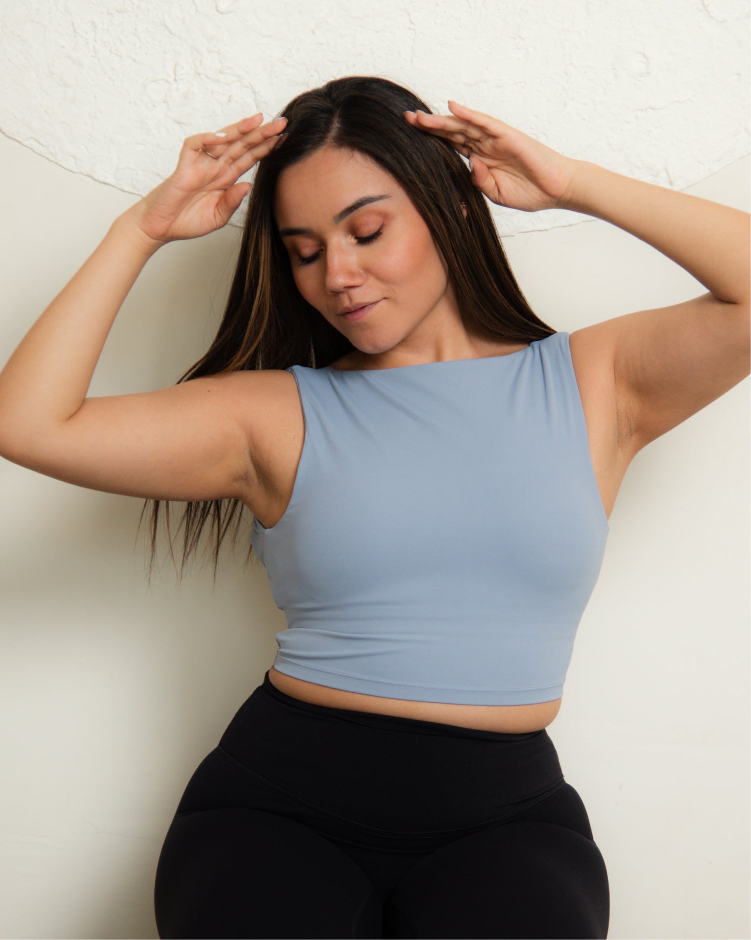 Top deportivo largo azul claro para mujer, diseño sin mangas tipo tank con escote alto y mayor cobertura, ajuste ceñido al cuerpo y acabado liso, ideal para entrenamiento y uso diario.