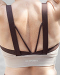 Top deportivo café para mujer con tirantes anchos en contraste color beige, escote redondeado y ajuste ceñido al cuerpo, diseño liso de estilo deportivo ideal para entrenamientos y uso diario.