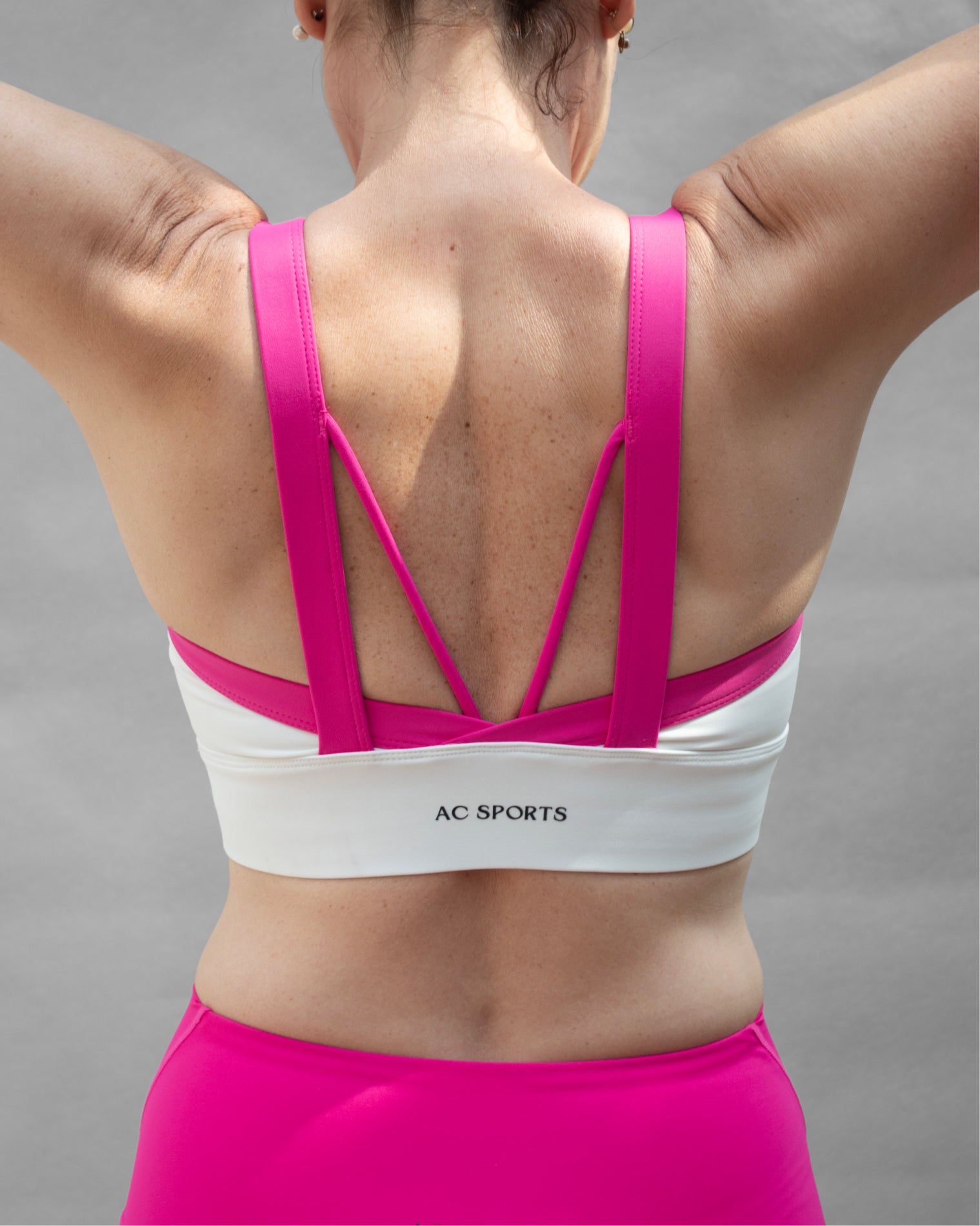 Top deportivo rosa para mujer con tirantes anchos en contraste color blanco, escote redondeado y ajuste ceñido al cuerpo, diseño liso de estilo deportivo ideal para entrenamientos y uso diario.