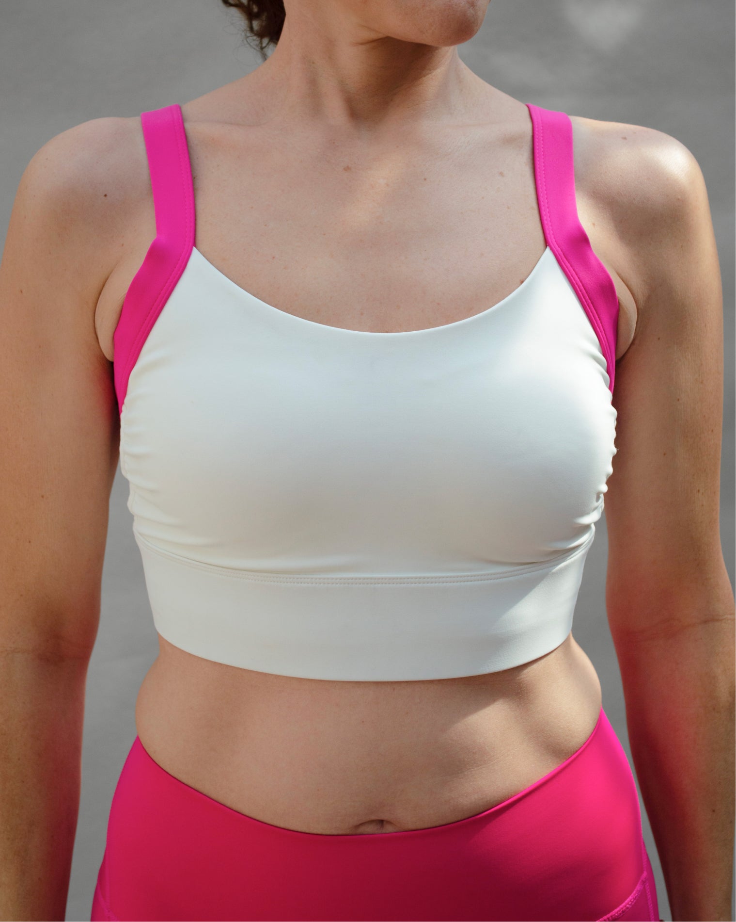 Top deportivo rosa para mujer con tirantes anchos en contraste color blanco, escote redondeado y ajuste ceñido al cuerpo, diseño liso de estilo deportivo ideal para entrenamientos y uso diario.