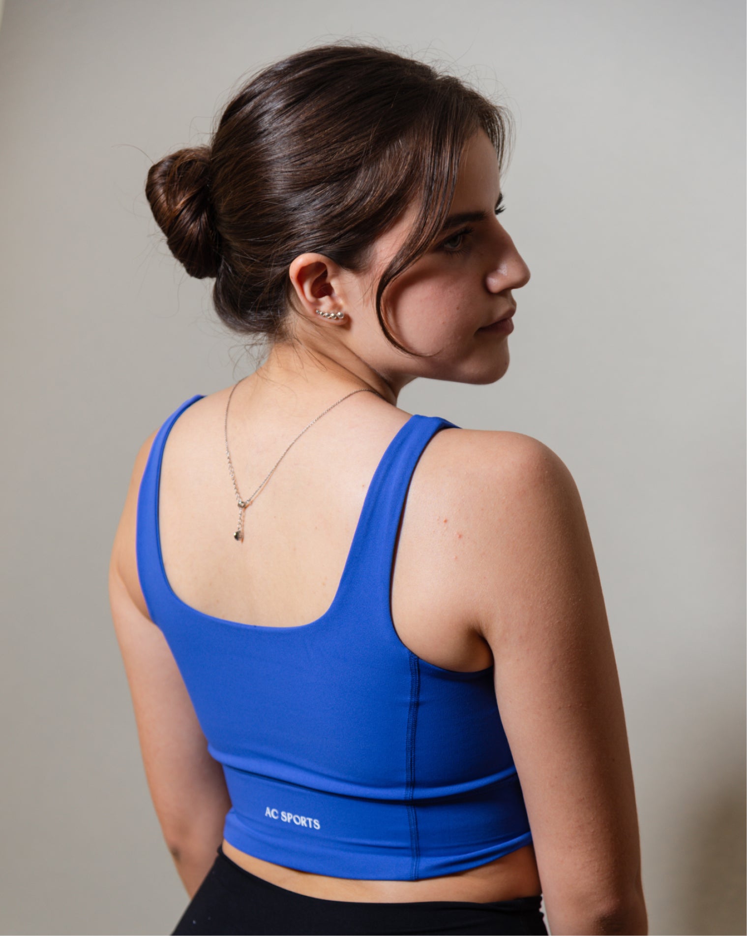 Top deportivo Azul para mujer con tirantes anchos, escote en forma de V y ajuste ceñido al cuerpo, diseño liso con banda inferior visible que aporta un ajuste firme, ideal para entrenamiento y uso diario.