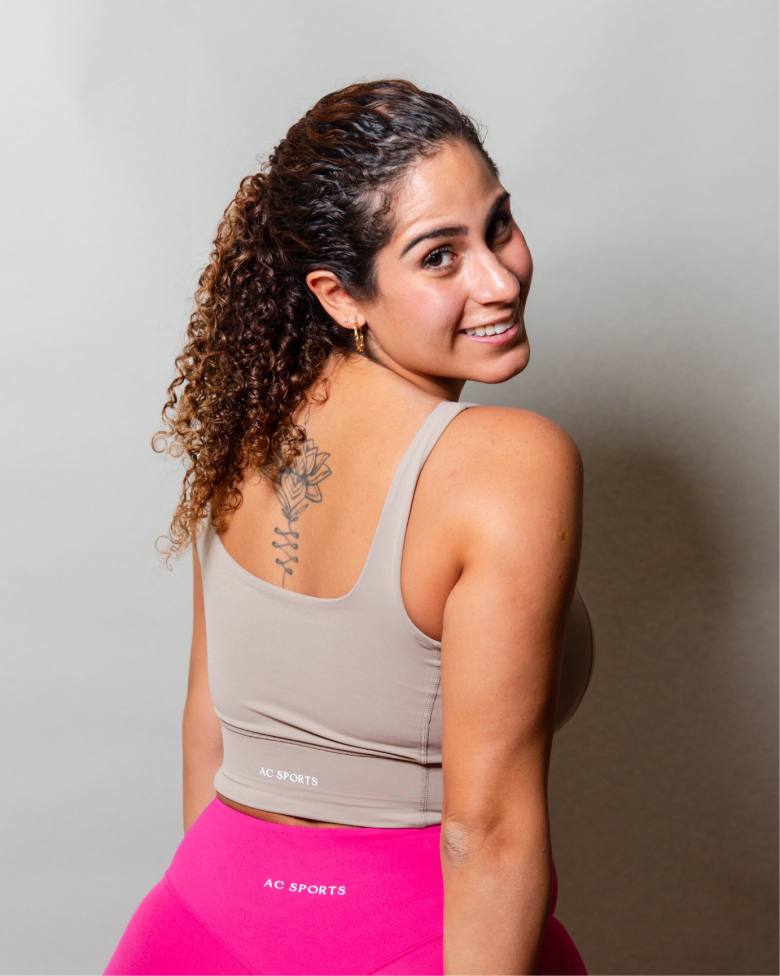 Top deportivo Beige para mujer con tirantes anchos, escote en forma de V y ajuste ceñido al cuerpo, diseño liso con banda inferior visible que aporta un ajuste firme, ideal para entrenamiento y uso diario.