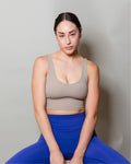 Top deportivo Beige para mujer con tirantes anchos, escote en forma de V y ajuste ceñido al cuerpo, diseño liso con banda inferior visible que aporta un ajuste firme, ideal para entrenamiento y uso diario.