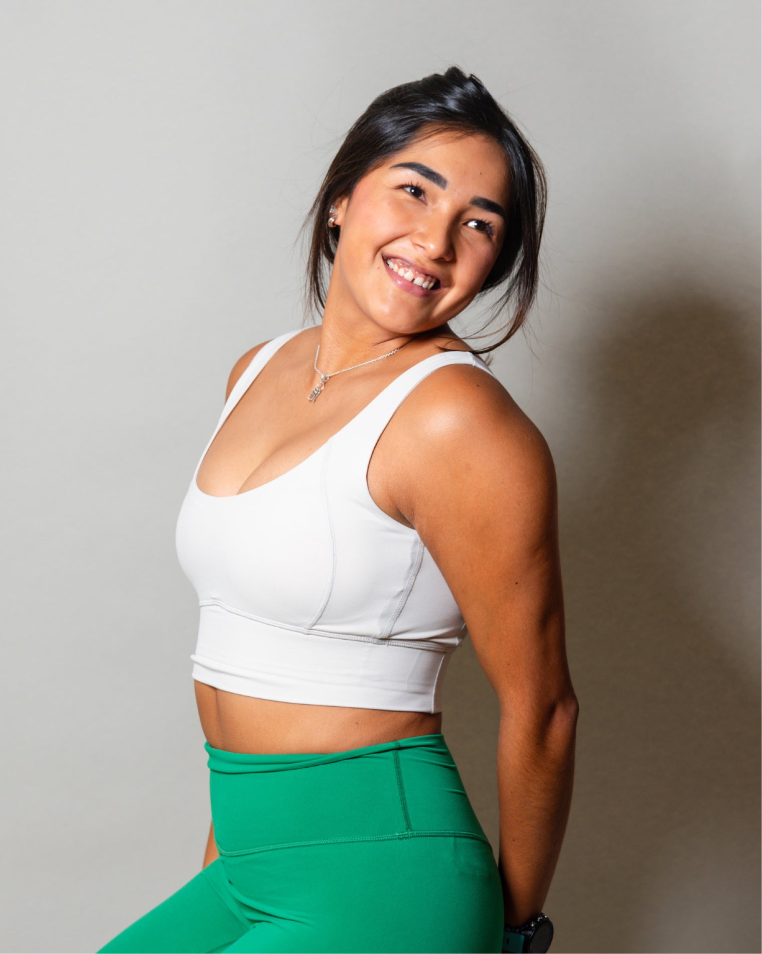 Top deportivo blanco para mujer con tirantes anchos, escote en forma de V y ajuste ceñido al cuerpo, diseño liso con banda inferior visible que aporta un ajuste firme, ideal para entrenamiento y uso diario.