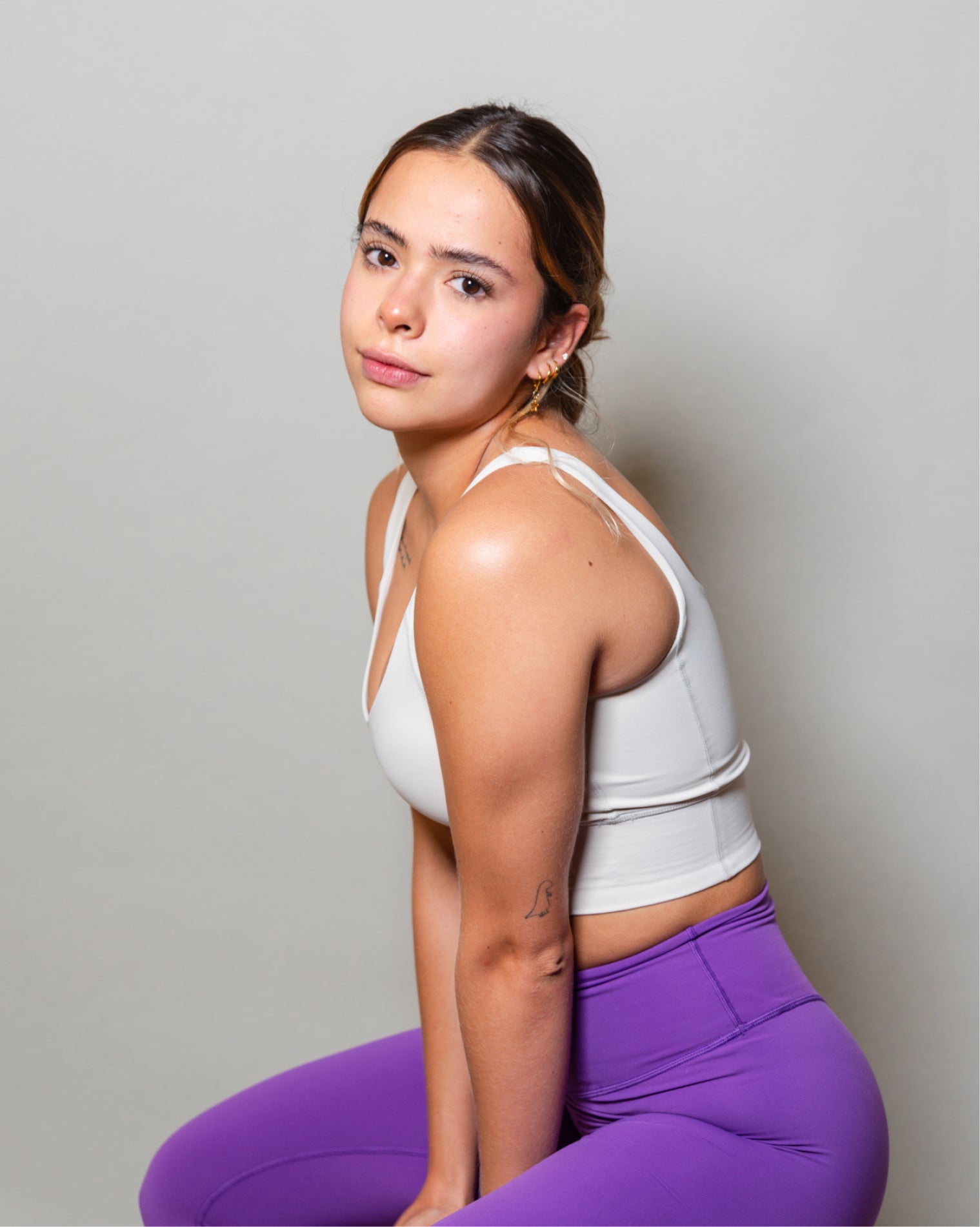 Top deportivo blanco para mujer con tirantes anchos, escote en forma de V y ajuste ceñido al cuerpo, diseño liso con banda inferior visible que aporta un ajuste firme, ideal para entrenamiento y uso diario.