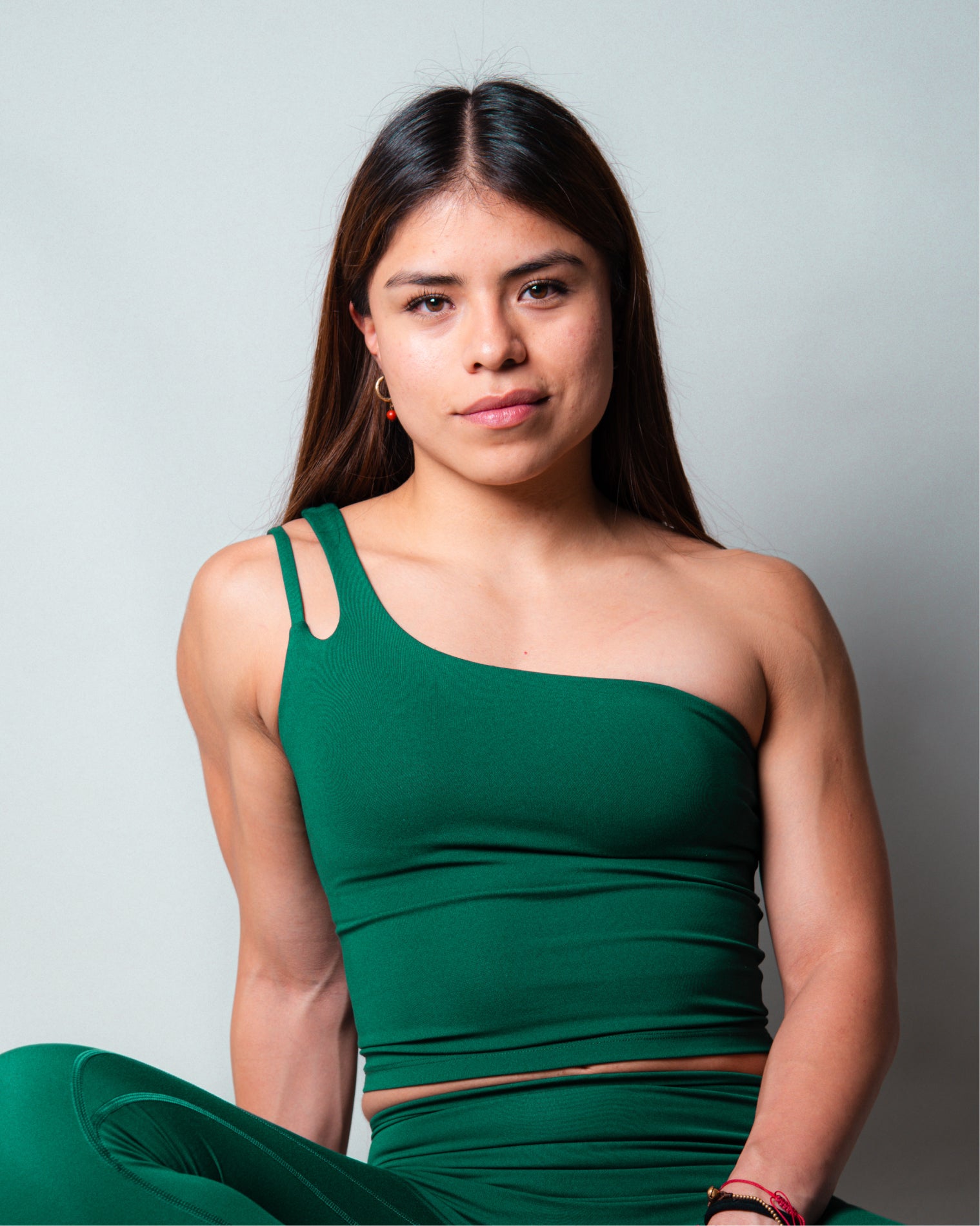 Top deportivo Siena color verde, diseño ajustado con escote recto y tirantes asimétricos.