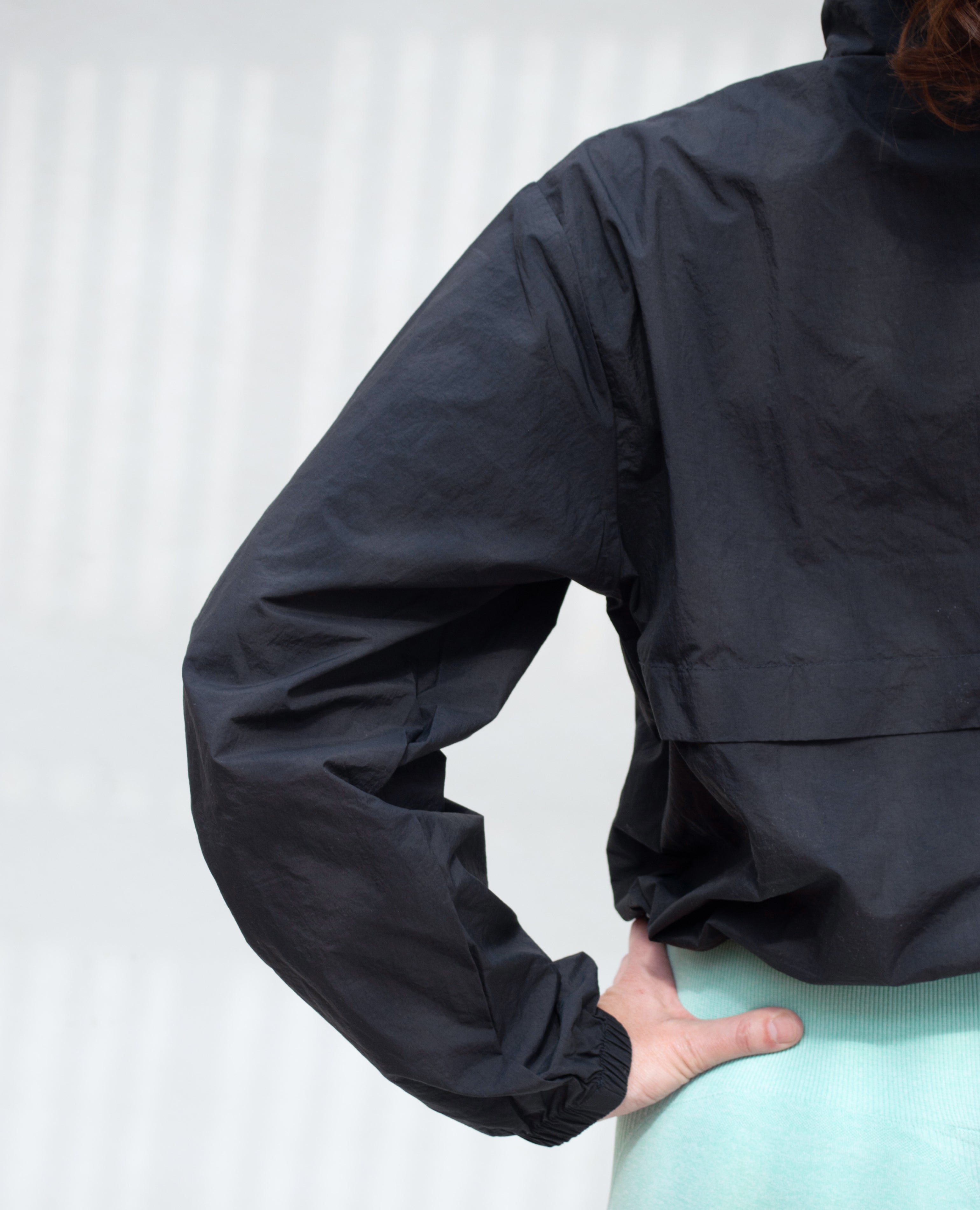 Chamarra deportiva corta de silueta levemente oversize con tela impermeable ligera, cuenta con cierre frontal medio y ajuste regulable en cintura con cordón interno para un fit personalizable y funcional.