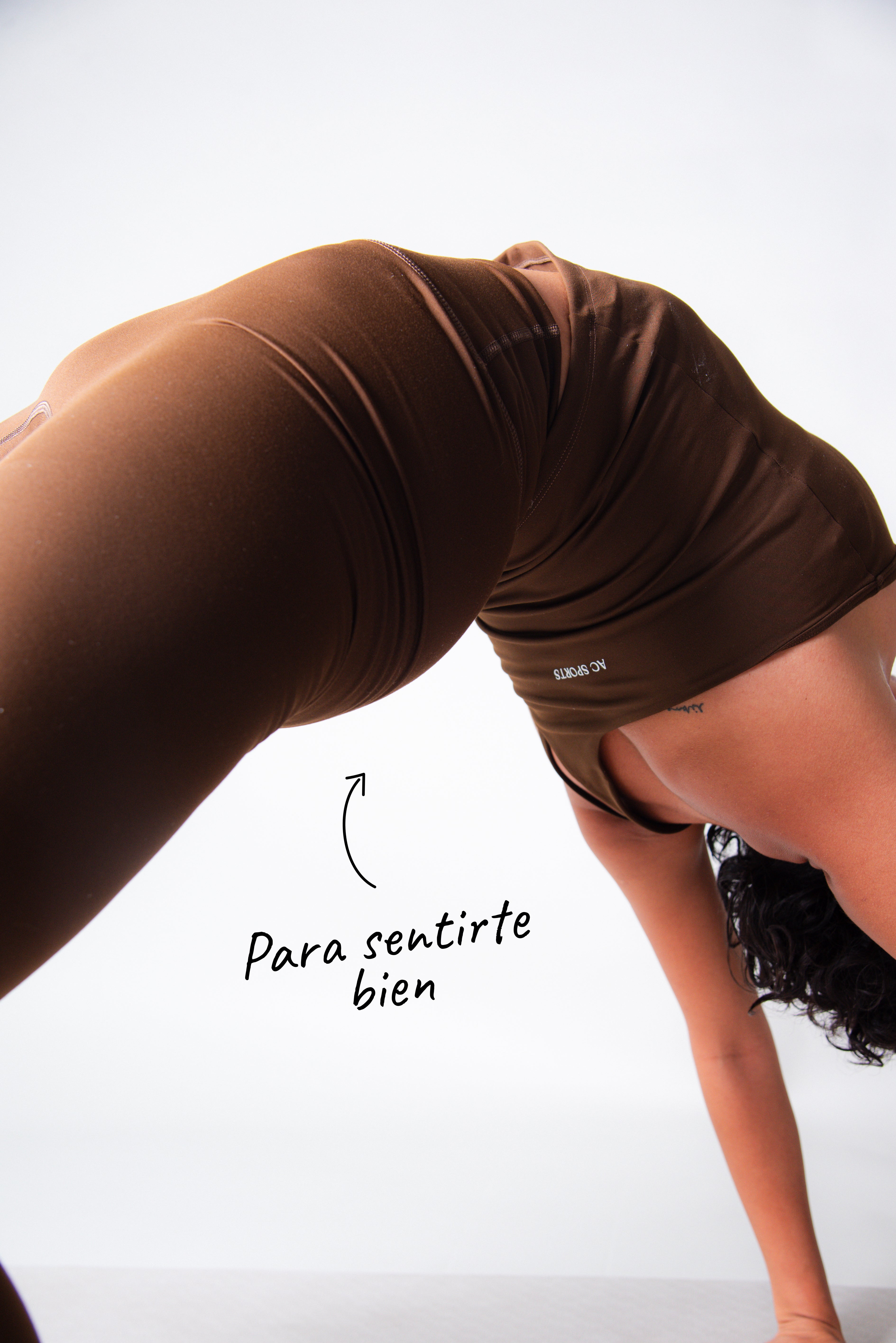Modelo femenina usando shorts deportivos color café AC Sports en postura de yoga, ropa diseñada para comodidad y movimiento